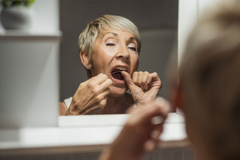 mature women flossing their teeth in their bathroom